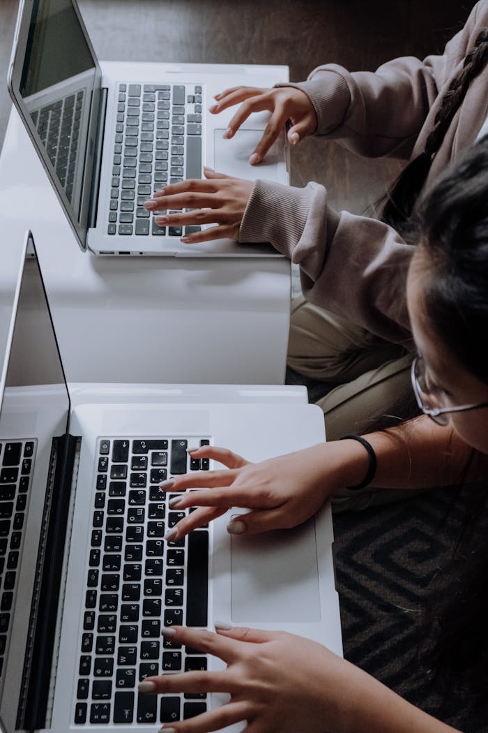 Children typing on laptops in an indoor learning environment, viewed from above.