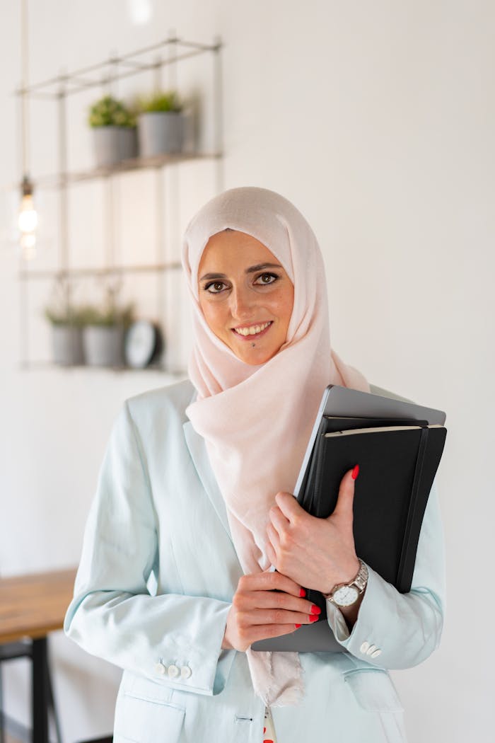 Young Muslim woman with hijab holding notebooks, symbolizing education and empowerment.
